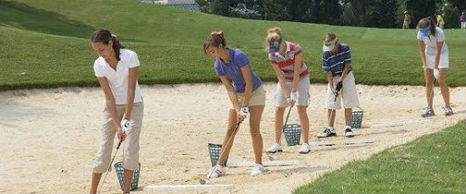 golf players practicing hitting out of a bunker