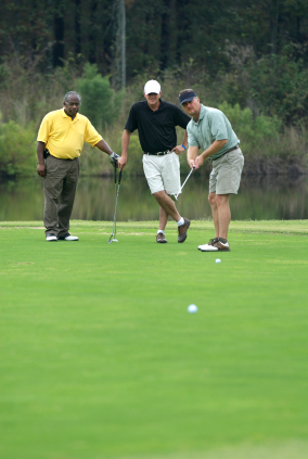 golfer putting while group looks on