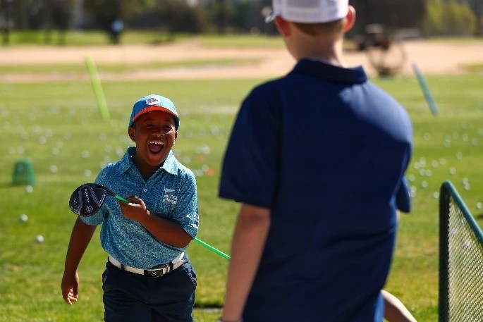 junior golfer smiling at the driving range