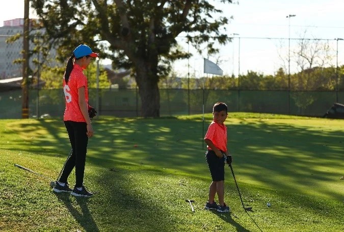 instructor and young student at the practice green